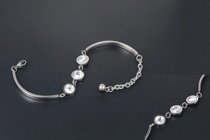 Macro view of silver titanium steel bracelet featuring three claw-set clear crystals