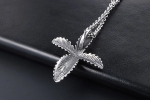 Detailed macro view of vintage stainless steel leaf cross pendant on black leather