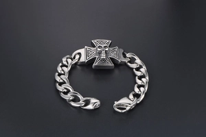 Detailed macro view of punk skull charm and iron cross on silver stainless steel bracelet