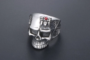 Close-up of vintage skull ring with a red gemstone inlay and spider web engraving