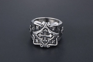 Close-up of vintage stainless steel gothic ring featuring a cross relief and ornate patterns