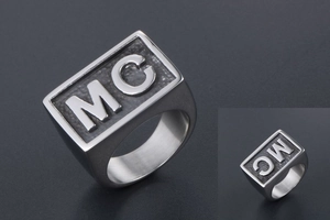 Detailed close-up of wide men's signet ring featuring embossed MC letters in vintage steel