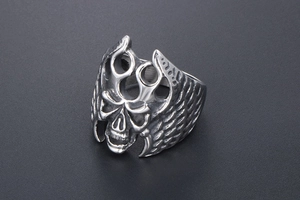 Macro detail of gothic skull ring with flame and wing engravings in vintage steel