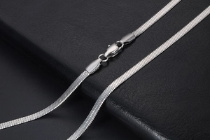 Macro detail of silver herringbone flat blade chain with polished lobster clasp