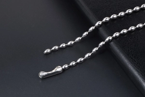 Macro shot of silver bead chain necklace with polished steel connectors on leather