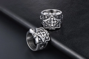 Macro shot of vintage stainless steel cross rings with detailed gothic floral engravings