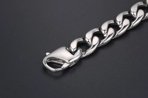 Close-up of polished silver stainless steel curb chain bracelet with large lobster clasp