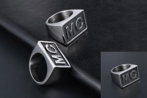 Macro detail of brushed stainless steel men's wide ring featuring MC letter engraving