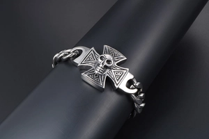 Macro detail of punk skull cross design on thick stainless steel chain bracelet for men