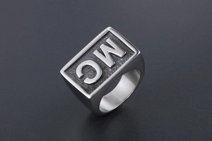 Detail view of square mens ring with MC letters on black matte surface