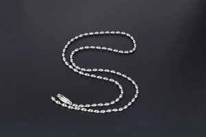 Detailed view of polished stainless steel ball chain necklace with mirror finish on gray