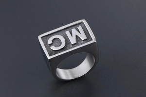 Macro shot of silver signet ring featuring MC lettering with matte textured background
