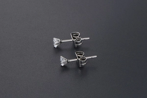 Detailed close-up of a minimalist silver titanium earring with six-prong set crystal stone