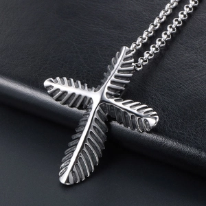 Vintage stainless steel cross necklace with leaf texture on black leather background