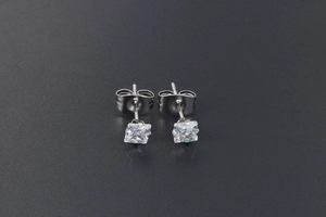 Macro shot of square-cut zircon stud earrings with butterfly backs on black background