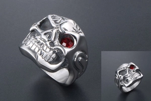 Macro shot of gothic steel ring with red stone eye and intricate skull carvings