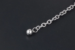 Macro detail of silver stainless steel chain bracelet with smooth round bead pendant