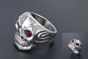 Macro shot of skull ring with red eye stones and detailed flame engraving on silver band