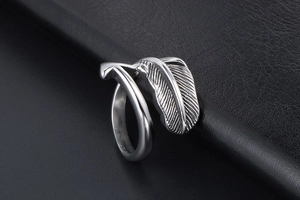 Macro shot of silver feather ring showing detailed texture on black leather surface