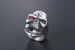 Macro view of punk skull ring with red gemstone eye and cigar detail in silver steel