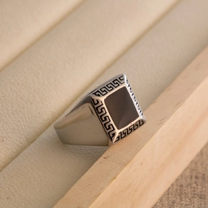 Detail of vintage signet ring with black enamel surface and Greek key pattern edges