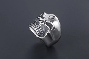 Macro shot of silver skull ring with embossed forehead detailing and punk rock aesthetic