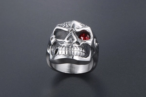 Detail view of gothic skull ring in stainless steel with a red gem inlay in the left eye