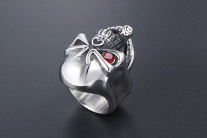 Macro shot of punk style stainless steel skull ring featuring a single red stone eye inlay