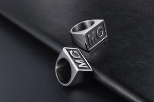 Detailed view of silver signet rings with MC engraving on square face and matte finish