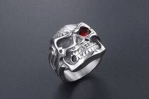 Macro detail of gothic skull ring in steel with a vibrant red stone inlay in the eye