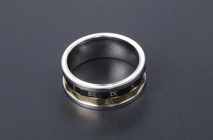 Vue macro d'une bague rotative en acier avec chiffres romains dorés sur sable sombre