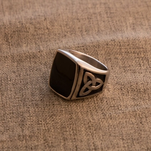 Detailed macro view of retro stainless steel ring with black enamel and Celtic knot patterns