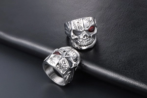Macro view of silver skull rings with red eye gems on black leather background