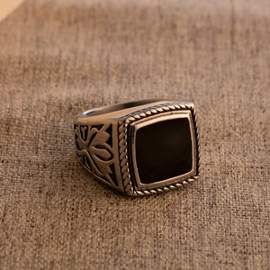 Detailed close-up of retro stainless steel signet ring with black enamel and side carving
