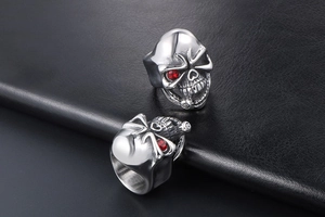 Close-up of punk skull rings in silver stainless steel with red zircon eyes on black leather