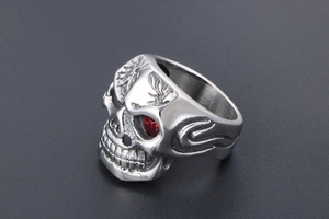 Macro detail of gothic skull ring in steel with red gem eye and flame engraving