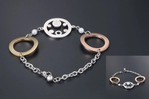 Detail eines dreifarbigen Metallarmbands mit Strassanhänger und weißen Perlen