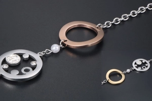 Details des roségoldenen Rings und silbernen Anhängers mit Strasssteinen und Perle