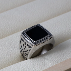 Macro shot of men's vintage steel ring with square black stone and floral carving