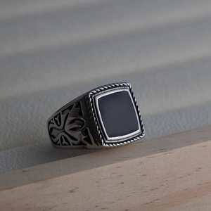 Macro shot of retro stainless steel men's ring with black inlay and floral side engraving