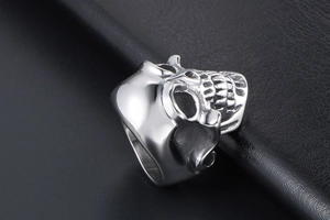 Gros plan d'une bague tête de mort punk en argent sur un fond en cuir noir texturé