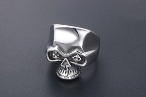 Gros plan d'une bague tête de mort en acier avec nez en pique et motifs de poker