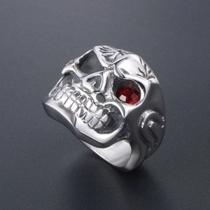 Punk gothic skull ring in stainless steel with red gemstone eye on dark background