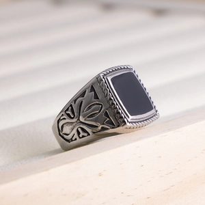 Macro shot of vintage steel ring featuring black onyx inlay and side cross relief detail
