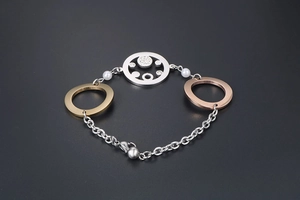 Detail eines dreifarbigen Metallarmbands mit verschlungenen Ringen und Zirkonia-Anhänger