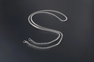 Close-up of polished silver box chain with lobster clasp on a black background