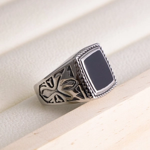 Detail of vintage men's signet ring featuring black enamel stone and cross carvings