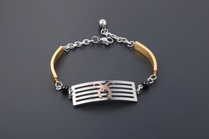 Macro detail of tricolor stainless steel bracelet with bow accent and lobster clasp
