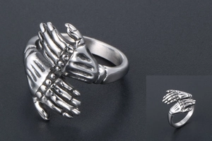 Detail of vintage punk ring showing two realistic skeleton hands hugging in silver steel