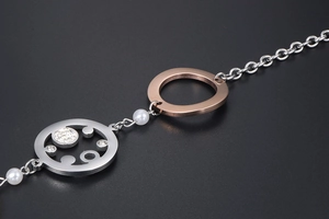 Makroaufnahme der Silberkette mit roségoldenem Ring, Perle und funkelnder Strass-Scheibe